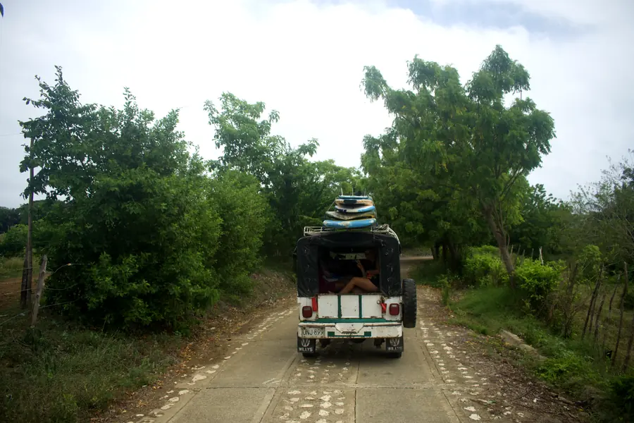 Jeep Willys con tablas de surf recorriendo un camino rural