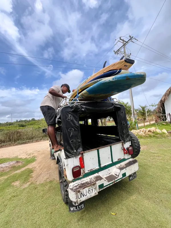 Instructor asegurando tablas de surf en el techo de un jeep Willys