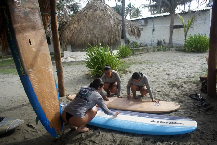 Alumnas preparando tablas bajo el kiosco de palma